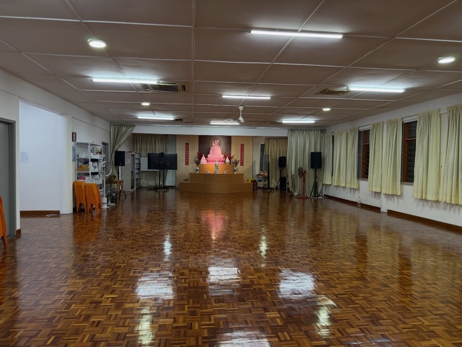 The spacious temple hall with polished wooden floors where participants rest