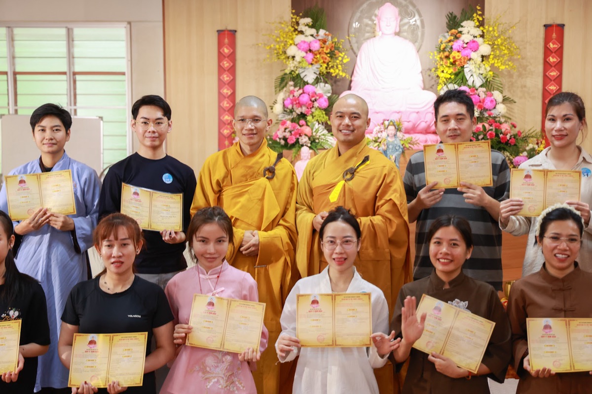 Participants smiling with their refuge certificates alongside the monks