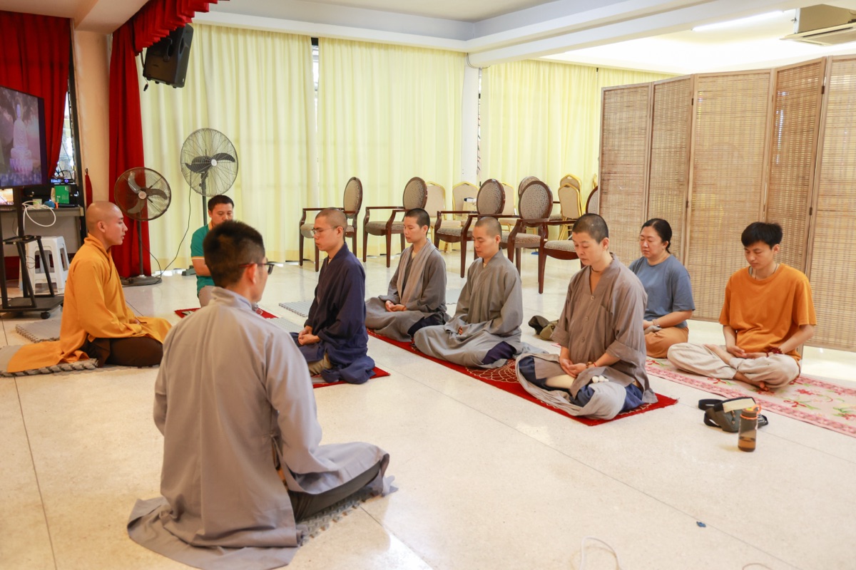 A monk guiding a small group in seated meditation practice