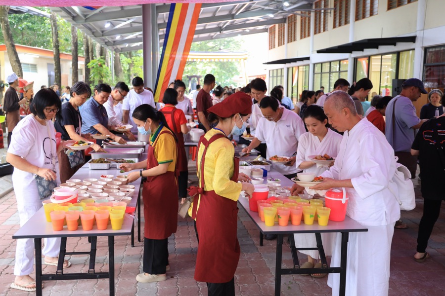 Volunteers serving vegetarian meals to participants at the temple