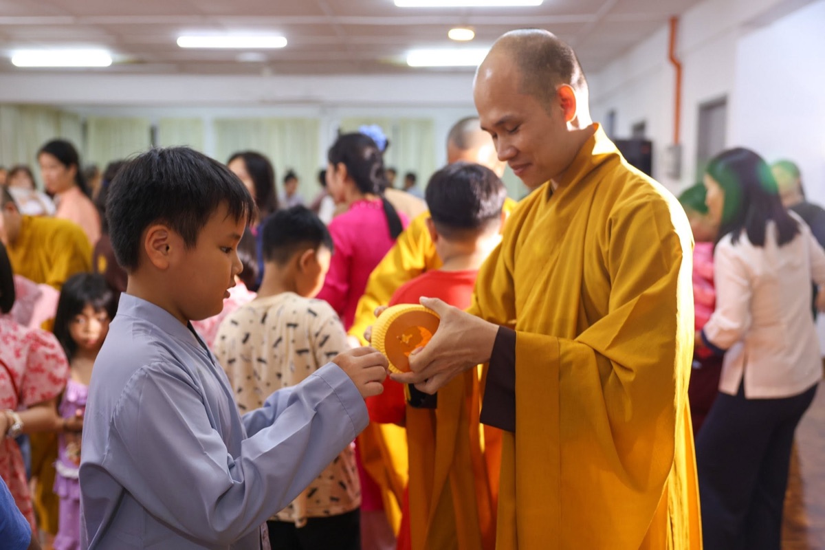 A monk handing a Mid-Autumn lantern to a young participant
