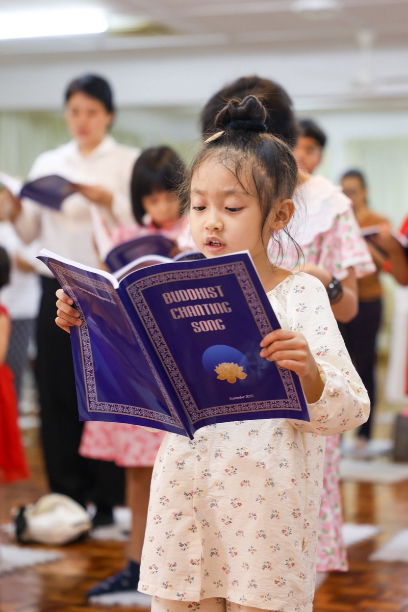 A young participant singing from the Buddhist chanting song book